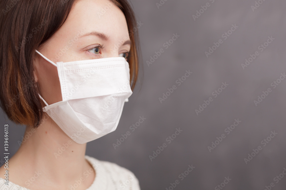 Girl in medical disposable mask looking at the camera. Protection against viruses and bacteria during the flu epidemic Girl in medical disposable mask looking at the camera. Protection against viruses and bacteria during the flu epidemic