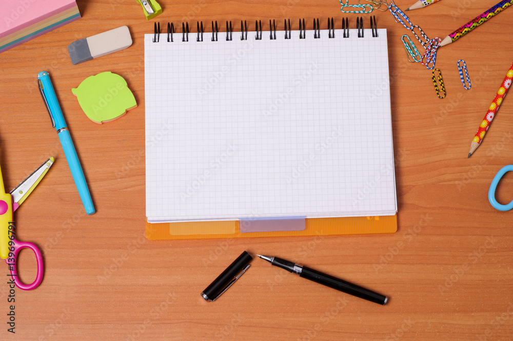 Top view of office tools with blank notebook on wooden table