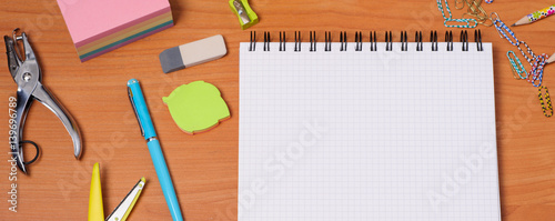 Top view of office tools with blank notebook on wooden table