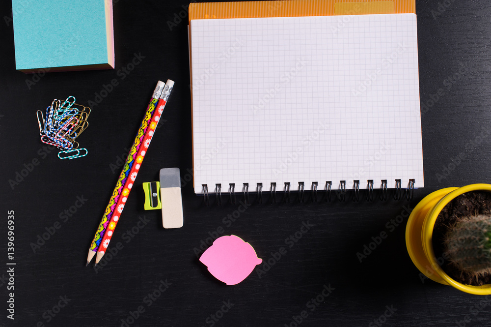 Top view of office tools with notebook on black background Top view of office tools with notebook on black background
