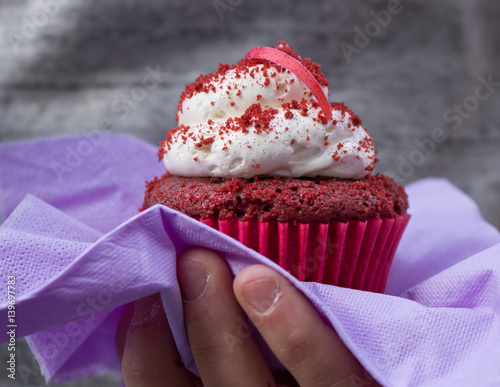 Dolce Cupcake Rosso tenuto in Mano da una Ragazza, con Tovaglia e Formina photo