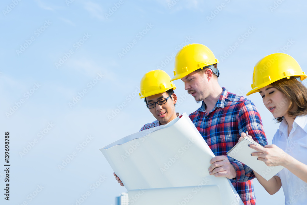 Engineer group and worker meeting, discussion with construction blueprint on site work with blue sky background Engineer group and worker meeting, discussion with construction blueprint on site work with blue sky background