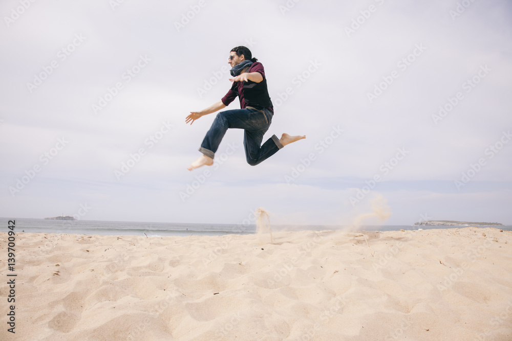 young man jumping high on the sand isolated on the beach