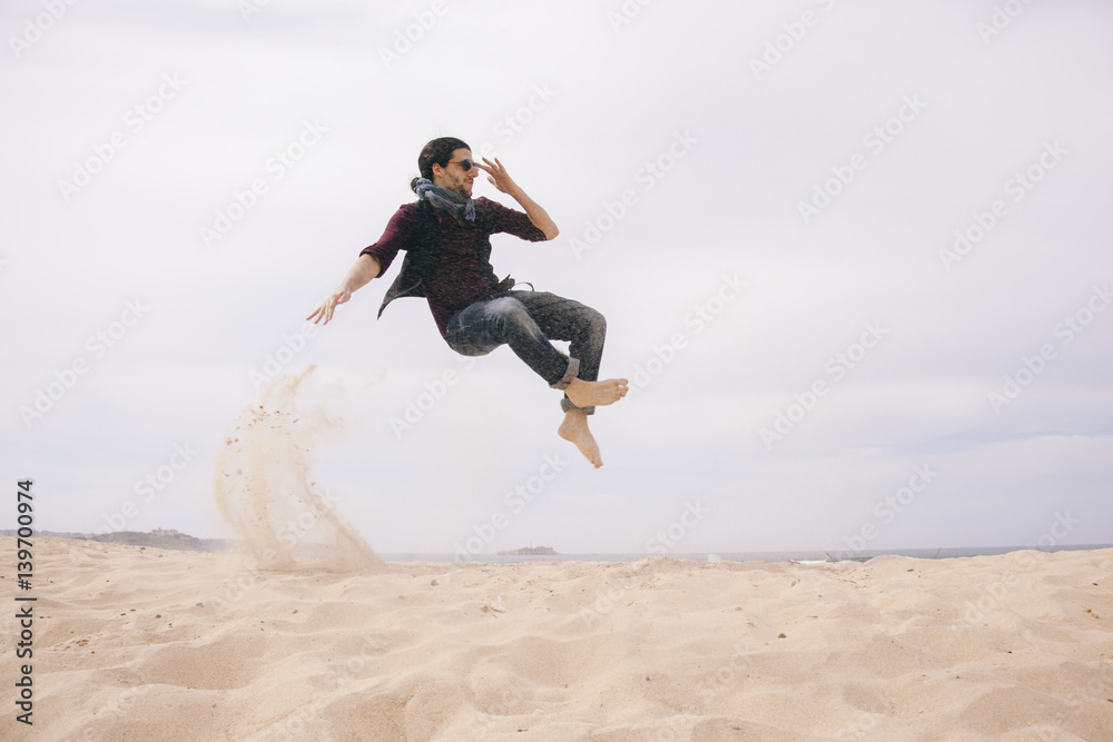 energetic man jumping high isolated on the sand energetic man jumping high isolated on the sand