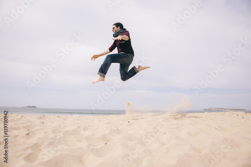 young man jumping high on the sand isolated on the beach