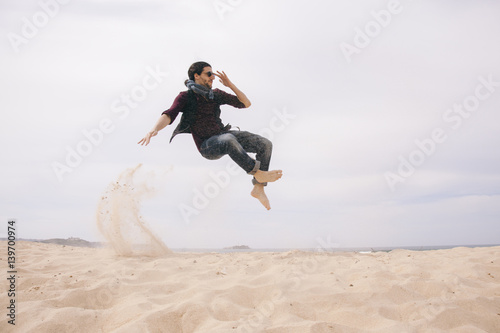 energetic man jumping high isolated on the sand