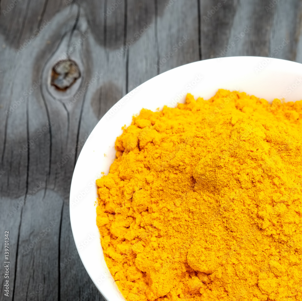 Turmeric powder in white cup on wooden floor. Turmeric powder in white cup on wooden floor.