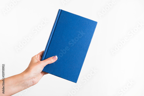 CLose up of female caucasian female woman holding blue book isolated on blue background. Horizontal color point of view shot.