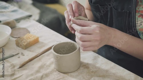 Wallpaper Mural Close-up of female hands ceramist. Woman potter making a clay mug and sticks handle. Ceramic ware handmade. The hands of the potter: a woman potter uses special tools and makes stein. Torontodigital.ca