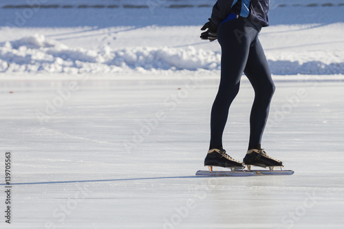 Man's legs on skates ice ring - winter sport at sunny day