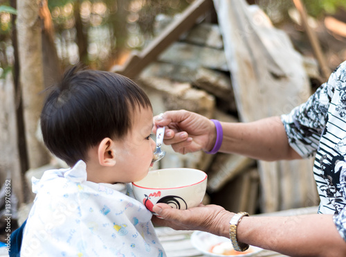 Asian baby boy feeding food by grand mother