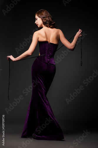 Back view of female wearing purple dress looking over shoulder. 