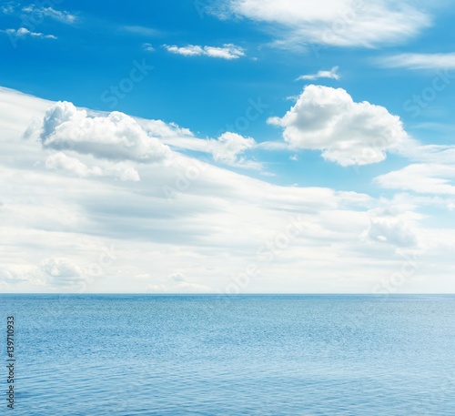 blue sea and sky with white clouds over it