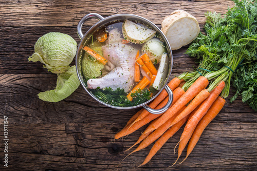 Top view of chicken soup -  broth on wooden table with vegetable. photo