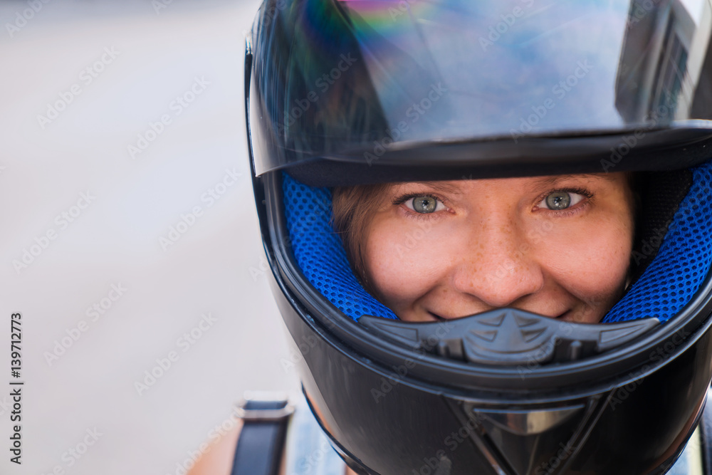 The concept of protection and safety on the road..A girl with beautiful eyes and a happy face in a black helmet with an open visor. The concept of protection and safety on the road..A girl with beautiful eyes and a happy face in a black helmet with an open visor.