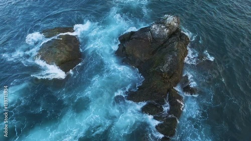 Flying over the cliff into the sea. Birds on a rock in the sea. Island with birds in the ocean