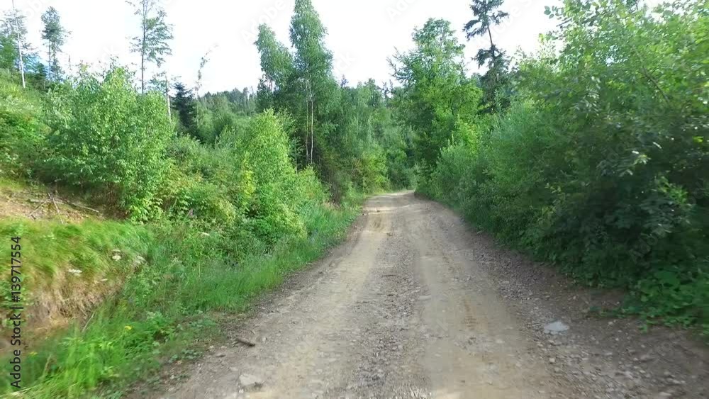 Earthy road away from the city. The sides of the road grow green hills Earthy road away from the city. The sides of the road grow green hills