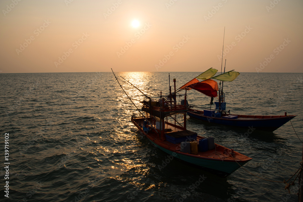 Silhouette fisherman's boat in the sea on sunset background