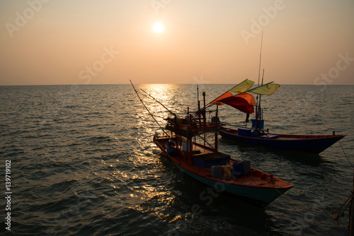 Silhouette fisherman's boat in the sea on sunset background