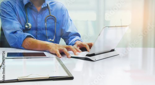 medicine doctor working with computer notebook and digital tablet  at desk in the hospital