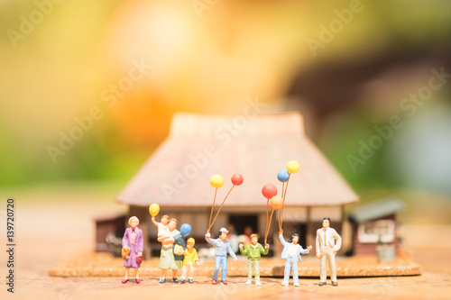 Miniature people, family and children with colorful ballons standing in front of house. International Day of Families