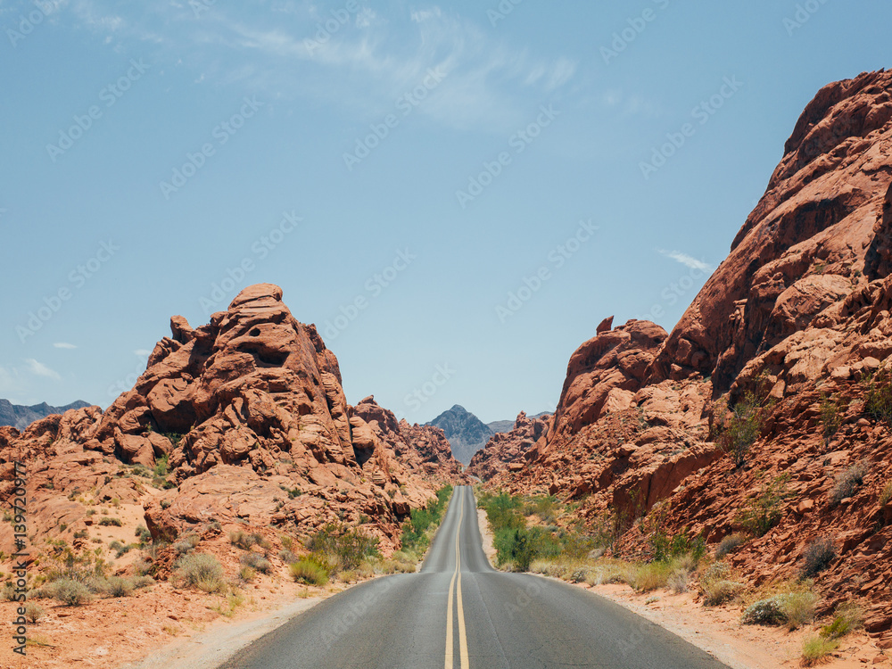 A narrow road carved through the red rocks in the valley of fire national park, in the heat of summer