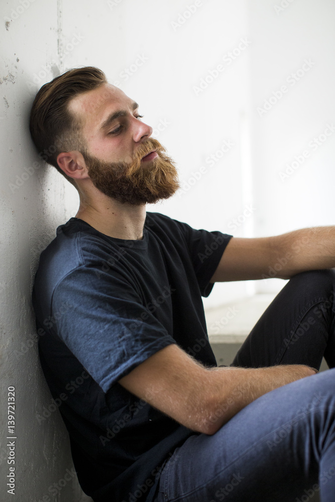 Bearded man sitting on stairs.