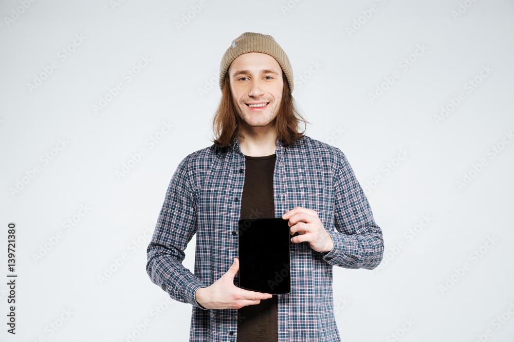 Smiling hipster showing blank tablet computer screen Smiling hipster showing blank tablet computer screen