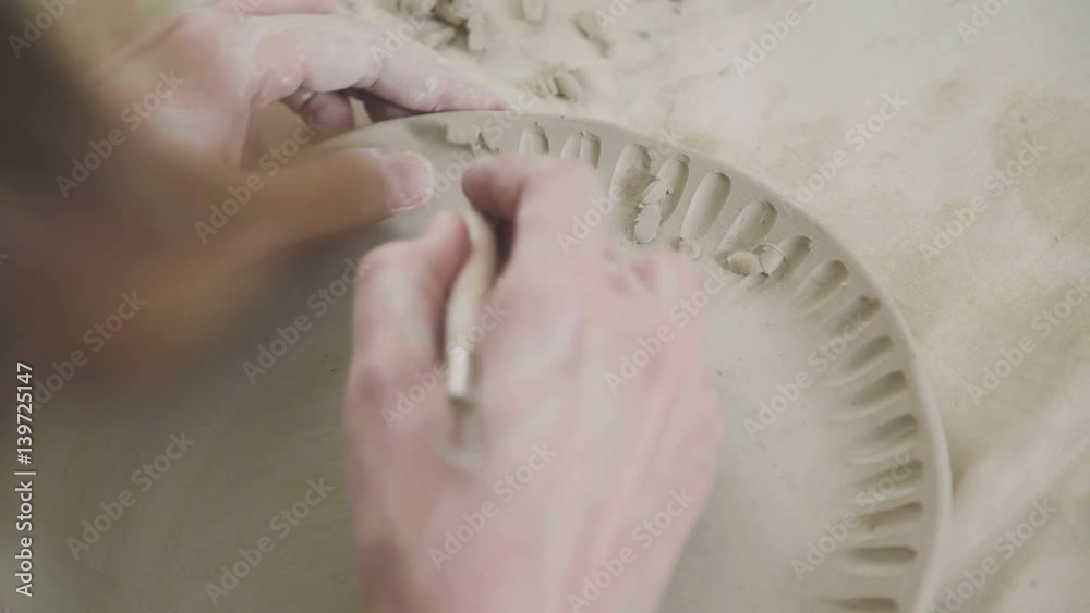 Potter does the clay pattern on the plate, using the stack. Ceramist ...