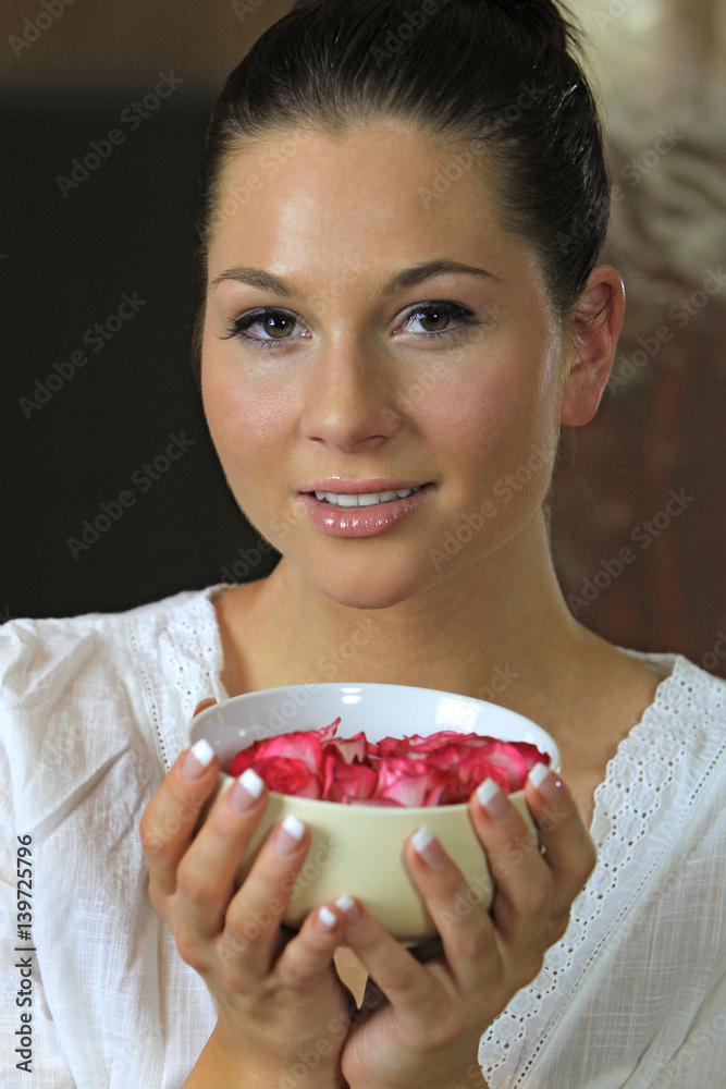 Pretty young woman smells on rose petals at aromatherapy in spa Pretty young woman smells on rose petals at aromatherapy in spa