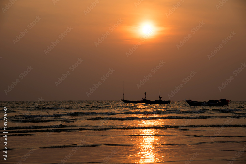 Silhouette fisherman's boats in the sea on sunset background