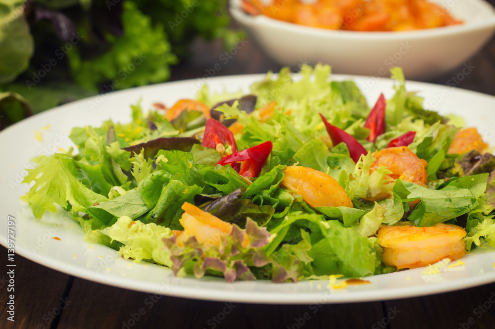 Salad with fried shrimps. Wooden background. Top view. Close-up