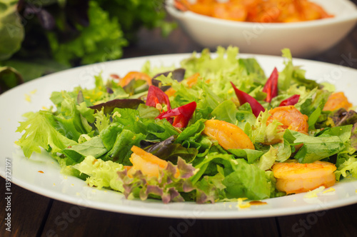 Salad with fried shrimps. Wooden background. Top view. Close-up