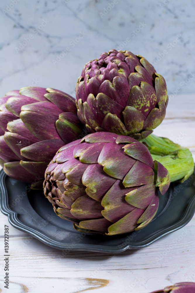 Obraz premium Fresh big Romanesco artichokes green-purple flower heads ready to cook