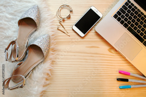 Top view wooden table desk for a fashion blogger on social media. Workspace with white fluffy rag, laptop and feminine accessories. Flat lay.