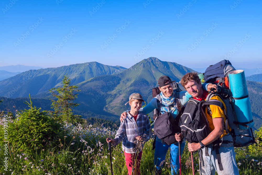 Happy family, hikers relax and enjoying life on the alpine meadow
