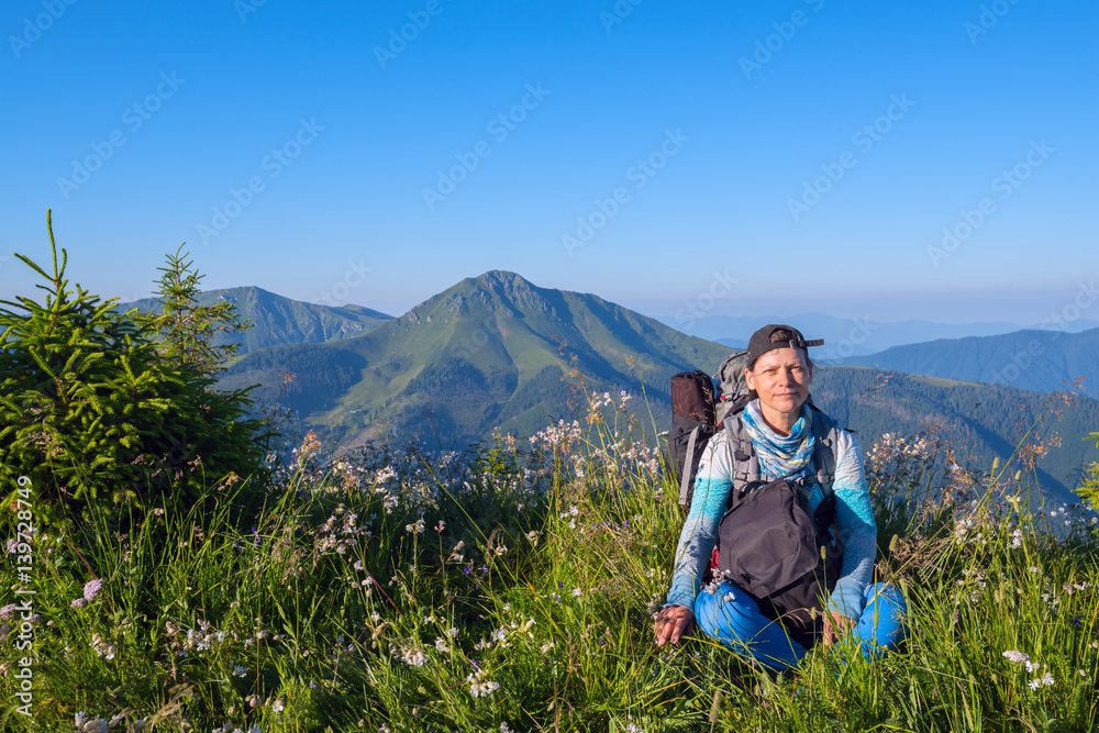 Sporty woman, traveler with backpack relax on the alpine meadow