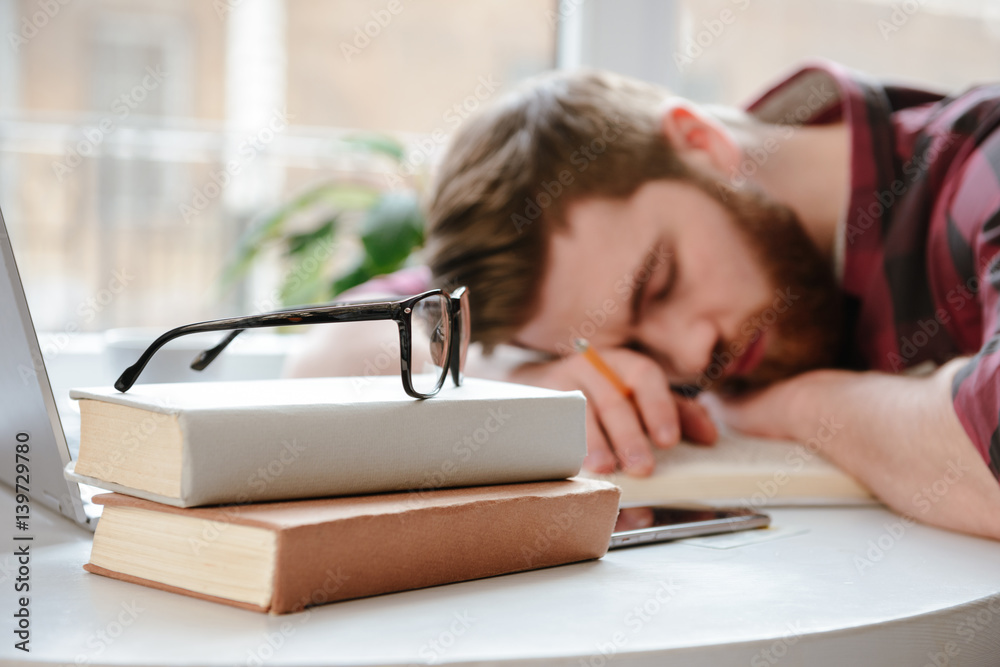 Sleeping bearded young man student lies on hands