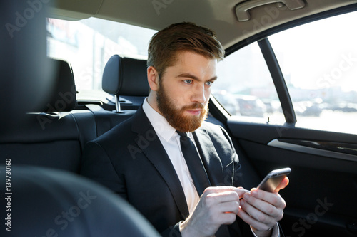 Portrait of a thoughtful business man typing on mobile phone © Drobot Dean