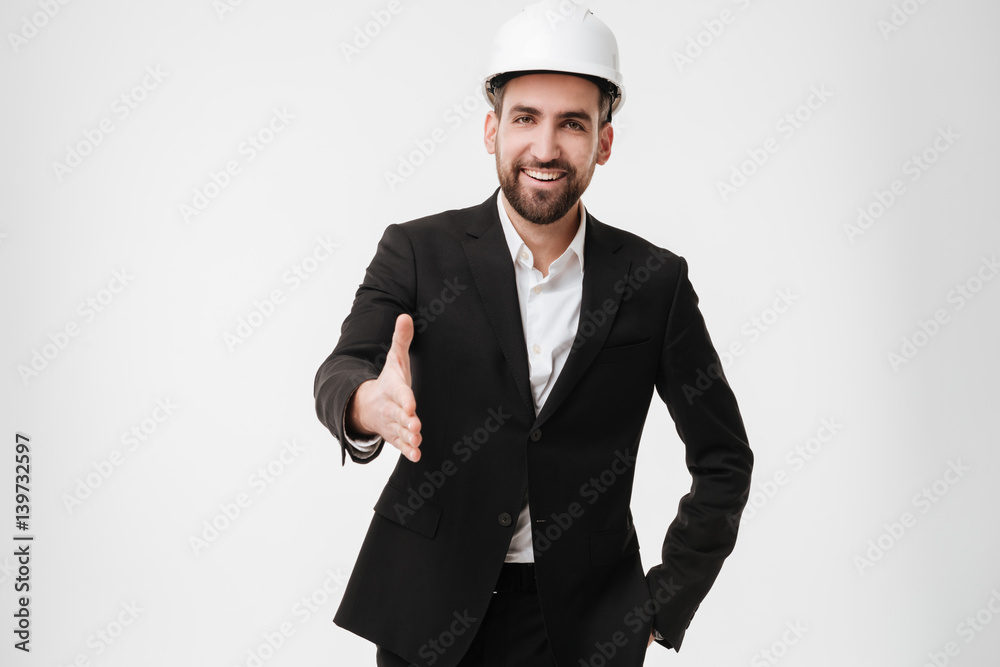 Cheerful architect wearing helmet gives a hand to camera.