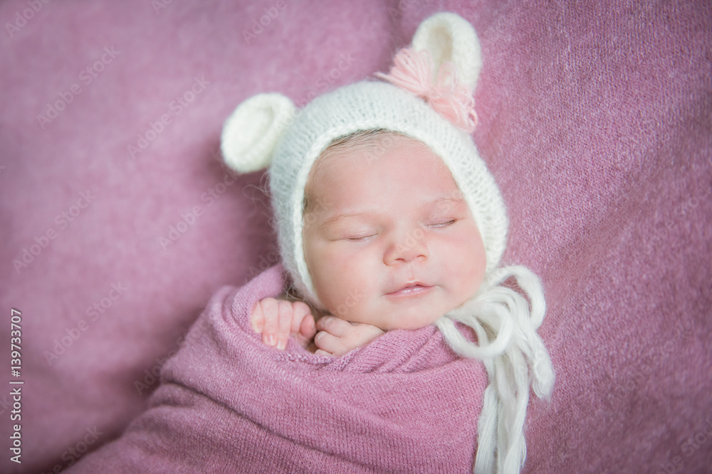 Smiling newborn baby sleeps in a hat with ears on a pink blanket Smiling newborn baby sleeps in a hat with ears on a pink blanket
