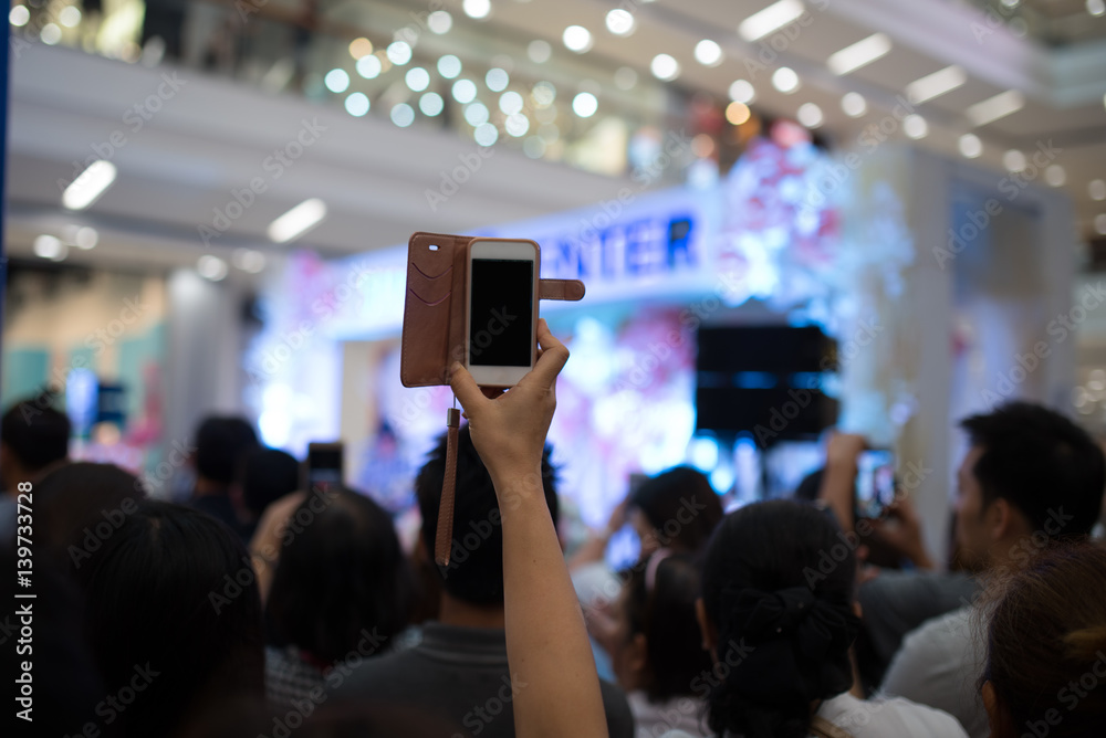 Fototapeta premium People hand using smartphone taking photo in concert