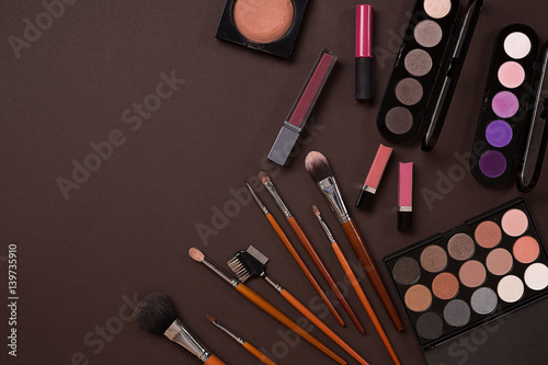 Various cosmetics and brushes on brown background