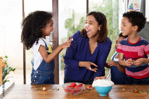 Une mère et ses enfants jouent à se mettre de la chantilly sur le nez dans la cuisine