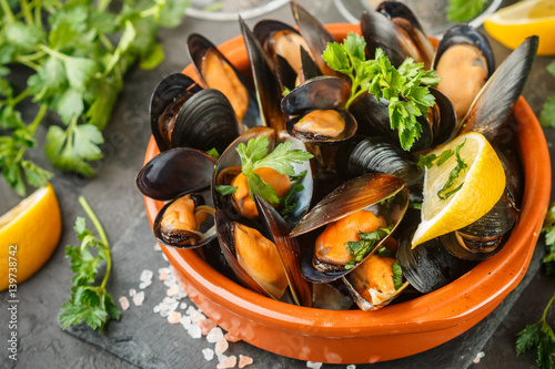 Mussels in wine with parsley and lemon. Seafood. Clams in the shells. Delicious snack for gourmands. Selective focus