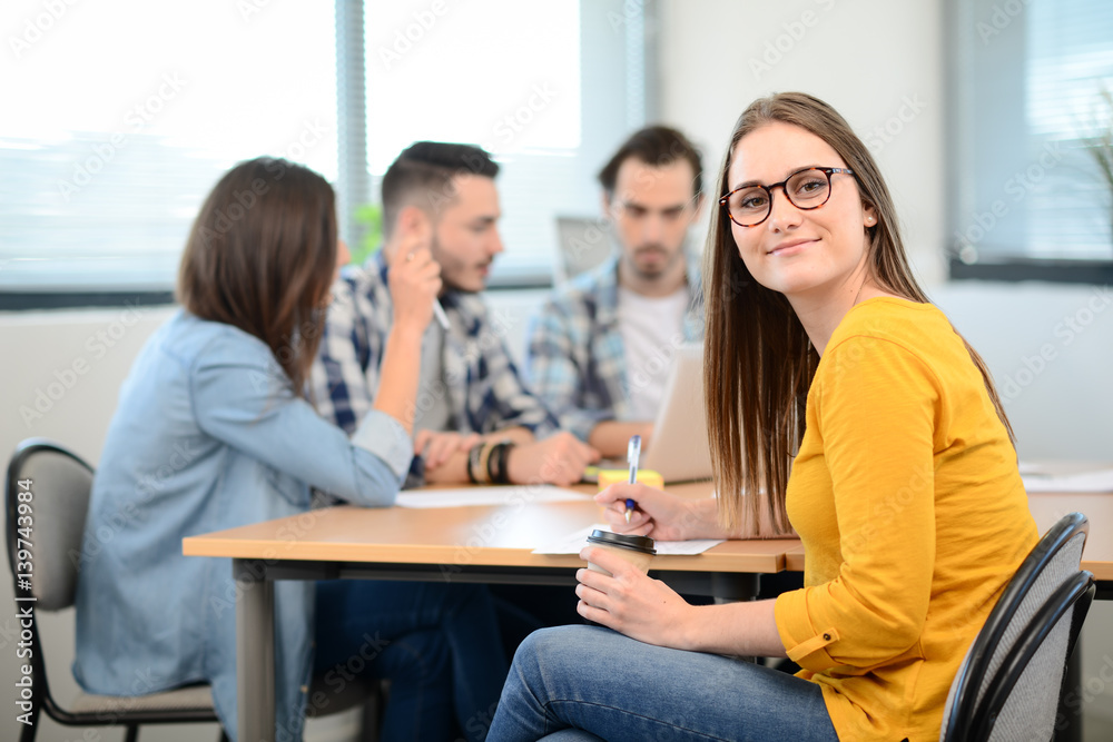 portrait of young woman in casual wear working in a creative business startup company office with coworker people in background