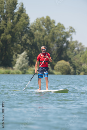 man enjoying a ride on the lake with paddleboard © auremar