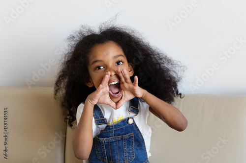 Une petite fille crie en mettant ses mains autour de sa bouche photo