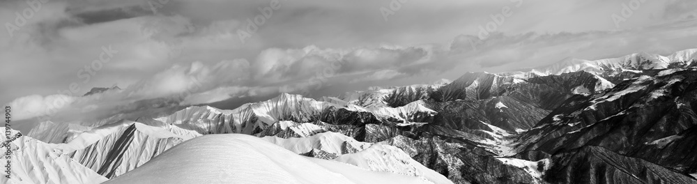 Black and white panorama of off-piste snowy slope and cloudy mountains Black and white panorama of off-piste snowy slope and cloudy mountains