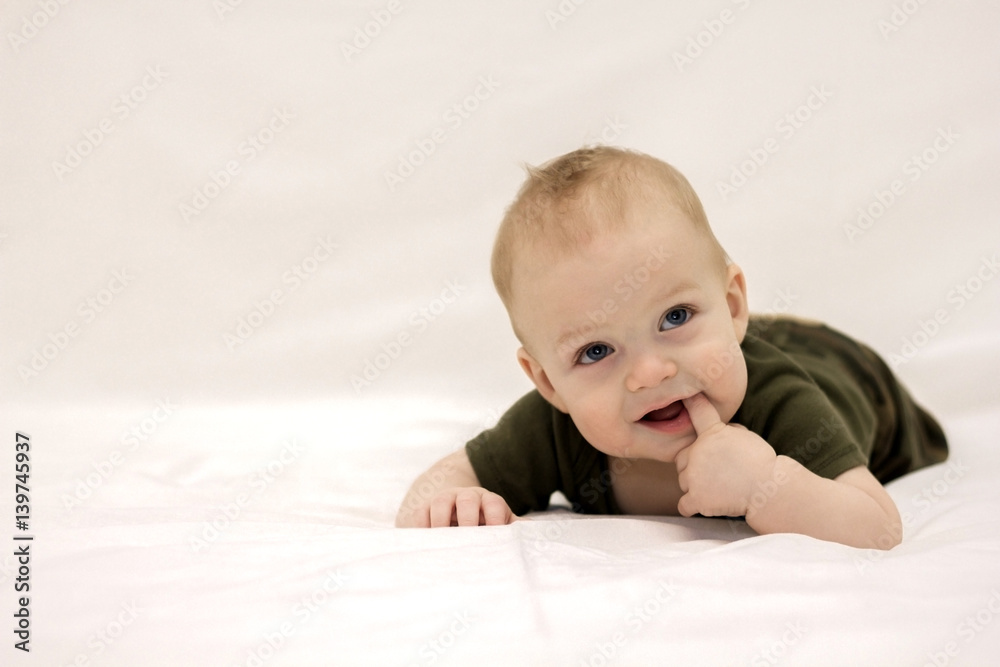 Smiling infant child lying on the white blanket